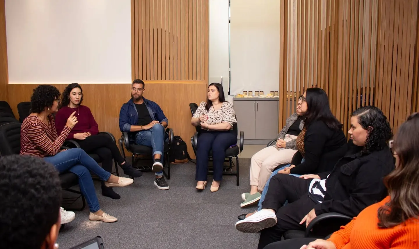 Karen Buratti conduzindo uma roda de conversa com profissionais sentados em círculo